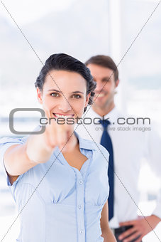 Woman pointing at camera with colleague in background