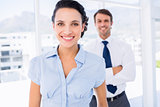 Smiling businesswoman with male colleague in background