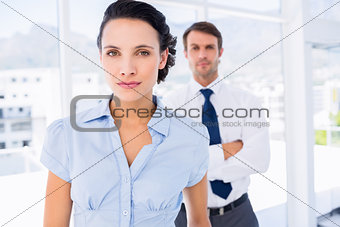 Serious businesswoman with male colleague in background