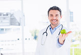 Portrait of a smiling male doctor holding an apple