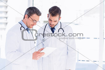Male doctors using digital tablet in medical office