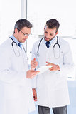 Concentrated two male doctors using digital tablet