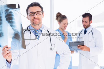 Male doctor examining xray with colleagues behind
