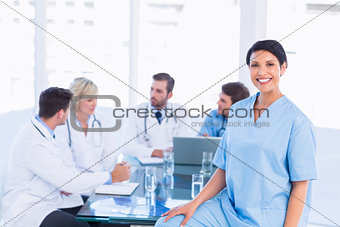 Smiling female surgeon with colleagues in meeting