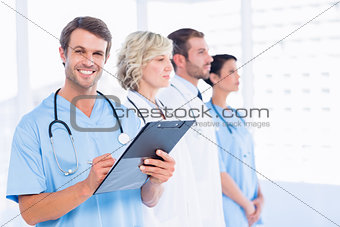 Male doctor writing reports with colleagues in medical office
