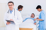 Doctor holding reports with patient and surgeon in background