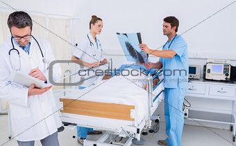 Doctors holding reports by patient in at hospital