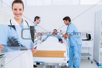 Doctor holding xray with surgeons and patient in hospital