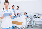 Doctor using digital tablet with colleagues and patient behind
