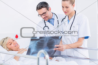 Doctors showing xray to patient in bed