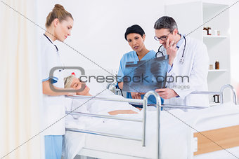 Doctors showing xray to patient in bed