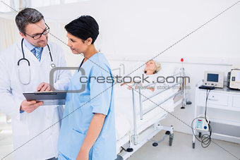 Doctors discussing reports with patient in background