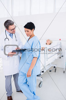 Doctors discussing reports with patient in hospital
