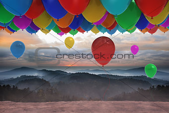 Many colourful balloons above landscape