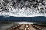 Train tracks leading to city under blanket of stars