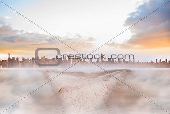 Dusty path in desert leading to city