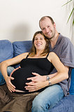 Happy husband embracing his pregnant wife on couch