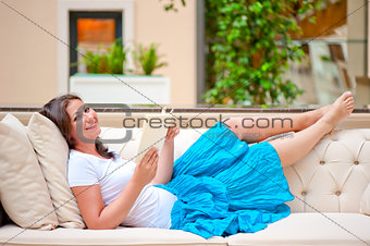 brunette on white sofa reading a book