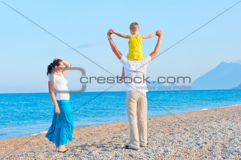family with son playing on the beach near the sea