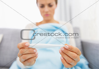 Closeup on young woman looking on thermometer
