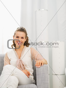 Portrait of happy young housewife sitting in living room