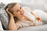 Portrait of smiling young housewife laying in living room