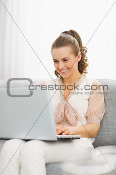 Happy young housewife using laptop