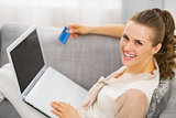 Portrait of smiling young housewife with credit card and laptop