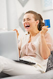 Happy young woman with credit card and laptop rejoicing