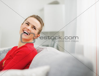 Young woman sitting on divan and looking on copy space