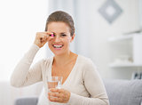 Portrait of happy young woman with pill and glass of water