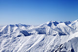 Snowy winter mountains and blue sky, view from ski slope