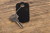 Blank tag and a key on wooden background 
