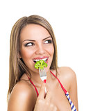 Happy cute young woman eating broccoli