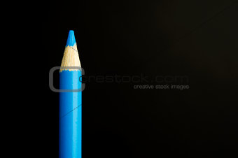 Blue pencil crayon on a black background
