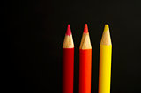 red, orange and yellow coloured pencil crayons on a black backgr