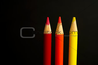 red, orange and yellow coloured pencil crayons on a black backgr