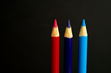 red, purple and blue coloured pencil crayons on a black backgrou