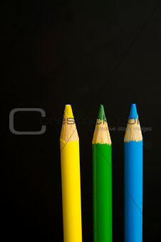 yellow, green and blue coloured pencil crayons on a black backgr