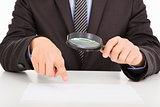 Businessman pointing through a magnifying glass to documents