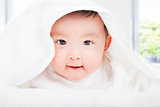 smiling baby smiling under a white blanket or towel