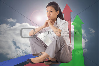 Composite image of businesswoman sitting cross legged with hands together