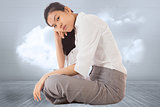 Composite image of businesswoman sitting cross legged leaning on hand