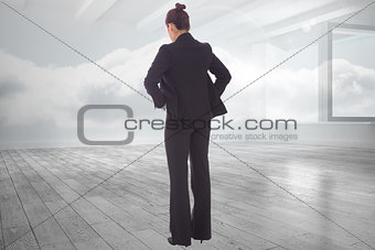 Composite image of businesswoman with hands on hips