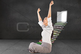 Composite image of businesswoman sitting cross legged cheering