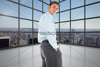 Composite image of serious businessman standing with hands in pockets