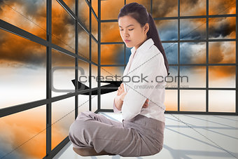 Composite image of businesswoman sitting cross legged with arms crossed
