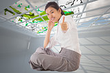 Composite image of businesswoman sitting cross legged showing thumb up
