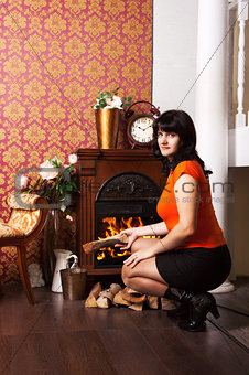 young beautiful woman sits near the fireplace