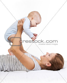 Happy young woman holding baby son while lying on back